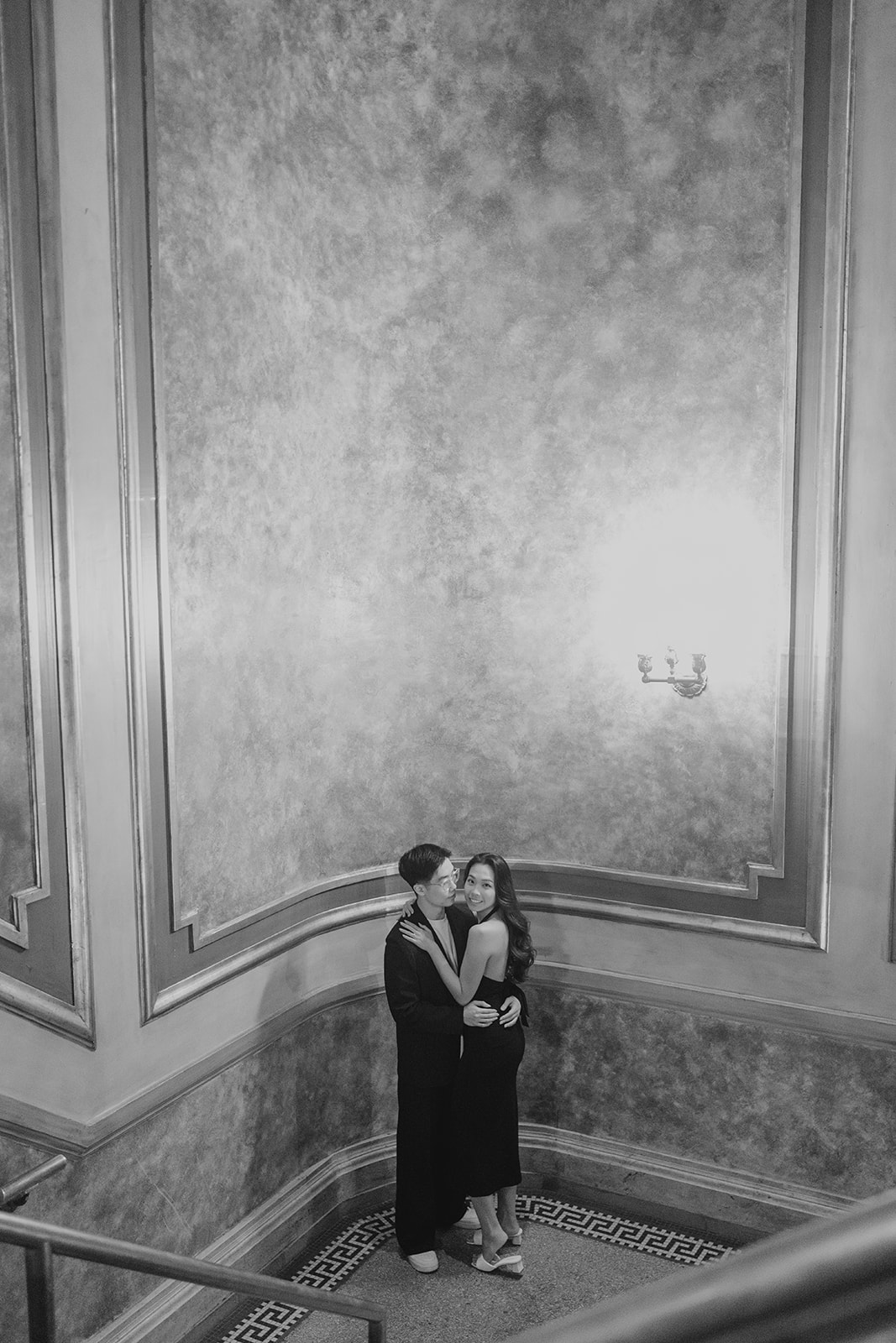 Bryan and Sheryl embracing on the stairs, in black and white